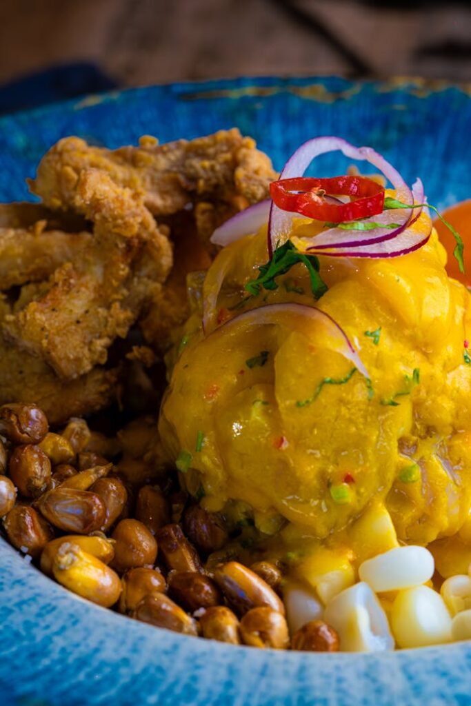 Close-up of a vibrant Peruvian ceviche with fried chicken and corn.